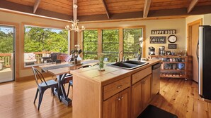 A spacious kitchen with wooden cabinets, a large island, and a dining area with a view of the outdoors. - Beech Mt Place - Cool Mtn Escape & Big Views! (Beech Mountain)
