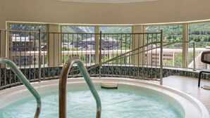 Een jacuzzi met metalen reling en uitzicht op gebouwen en groen.