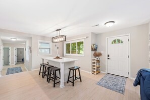 A modern kitchen with a white island, bar stools, and a pendant light.