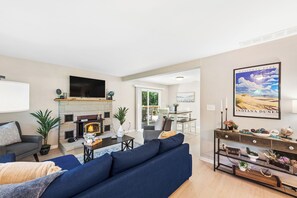 A modern living room with a fireplace, a television, and a dining area with outdoor access.