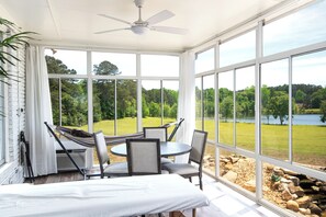 A sunroom with a view of a lake, a ceiling fan, and a hammock. - 3-bedroom house in pleasant Fayetteville with AC and comfort (Fayetteville)