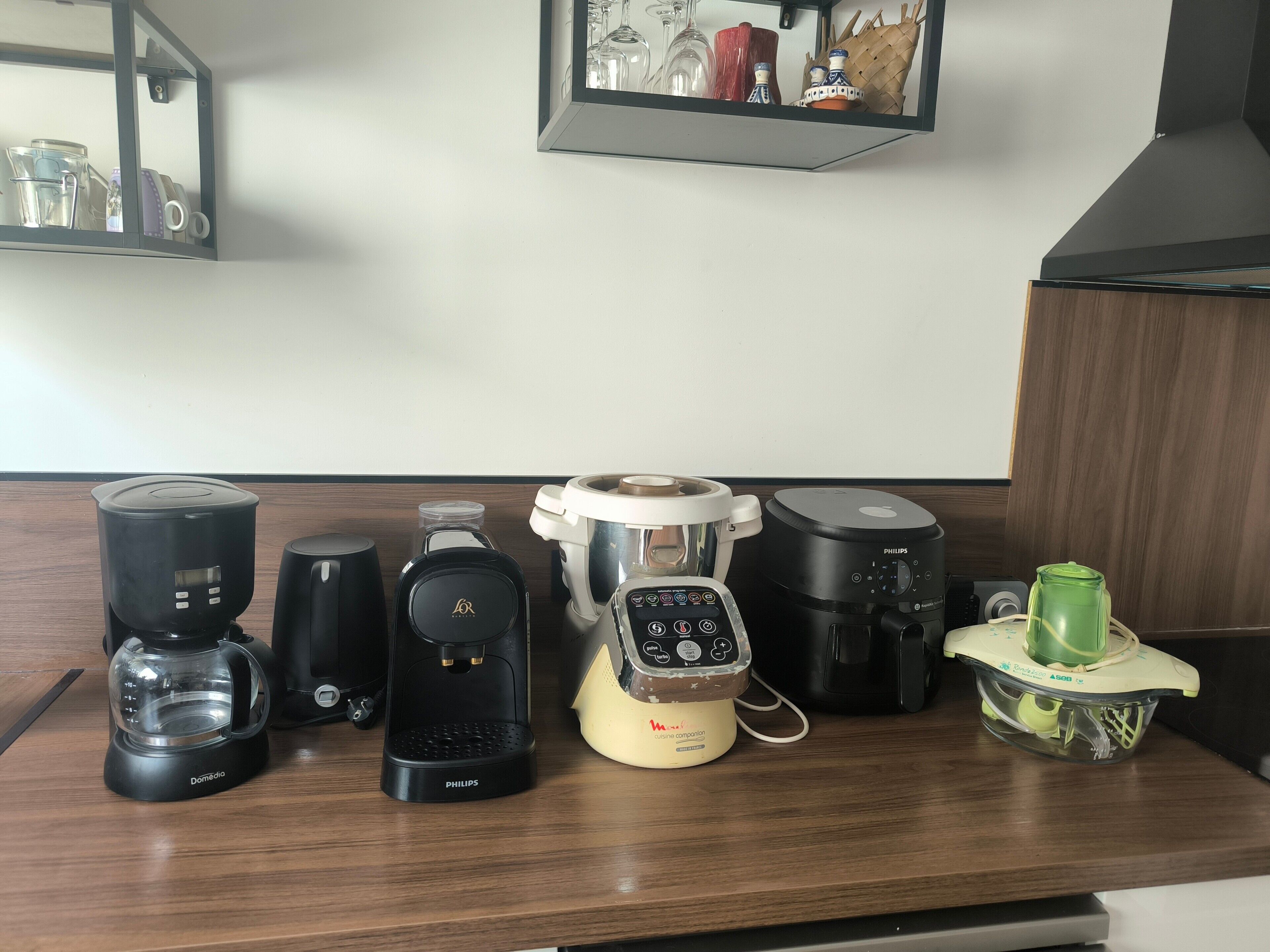 A kitchen counter with various appliances including a coffee maker, a blender, a rice cooker, and a food processor.