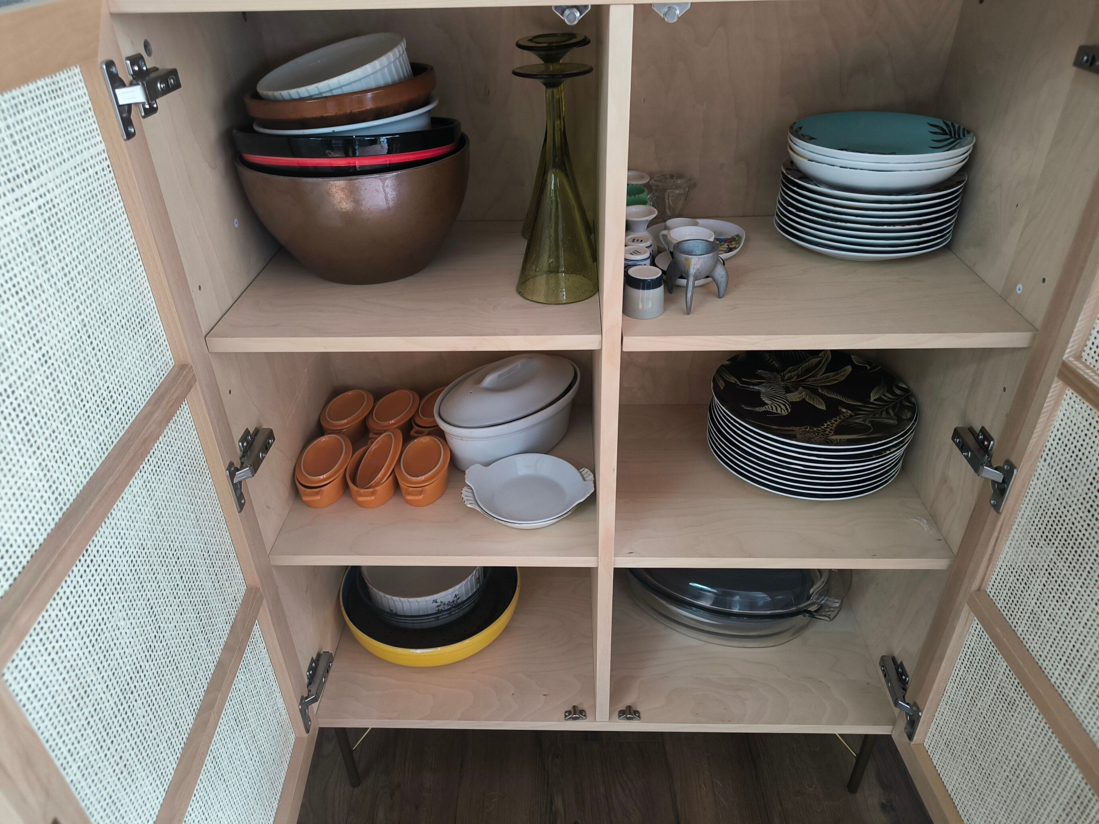 A wooden cabinet with shelves containing various kitchenware items.