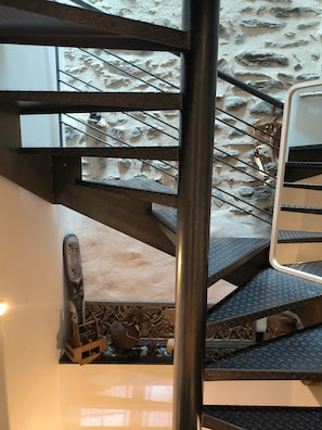 Eine Treppe mit einer Steinwand, Metallgeländern und einer hölzernen Bank am Fuß.