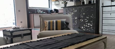 A modern bedroom with a bed, a desk, and a balcony.