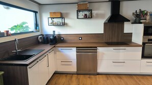 Een moderne keuken met een geïntegreerde vaatwasser, een koffiezetapparaat en een raam met uitzicht op groen.