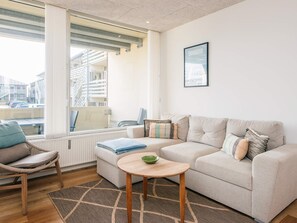 A modern living room with a sofa, a chair, a small table, and a window with blinds. - 4 Star Holiday Home in Fano (Fano)