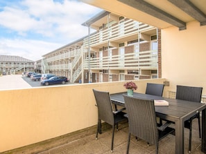 A balcony with a table and chairs, overlooking a parking area and a building with multiple floors and balconies. - 4 Star Holiday Home in Fano (Fano)