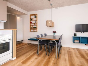 A modern kitchen with a built-in oven and a dining area with a wooden table and chairs. - 4 Star Holiday Home in Fano (Fano)