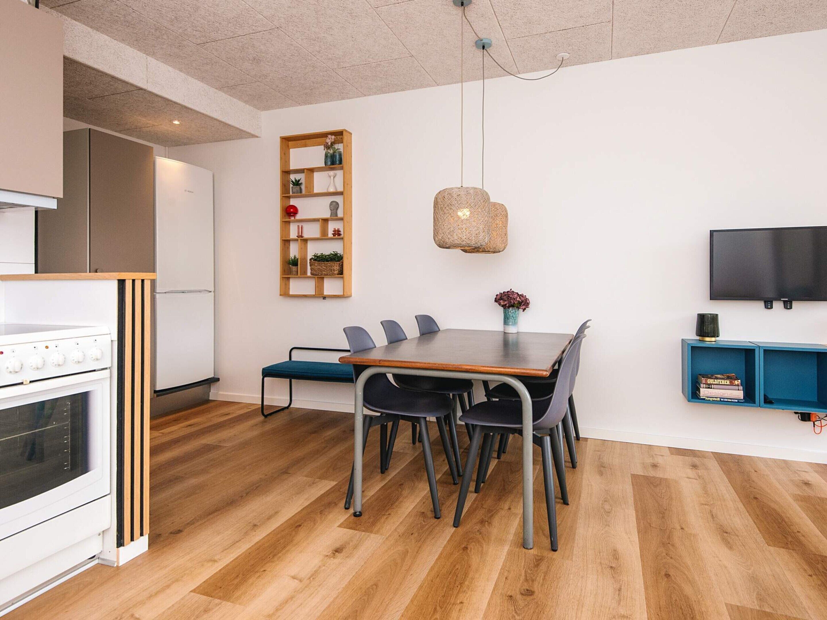 Eine moderne Küche mit eingebautem Ofen und einem Essbereich mit einem Holztisch und Stühlen.