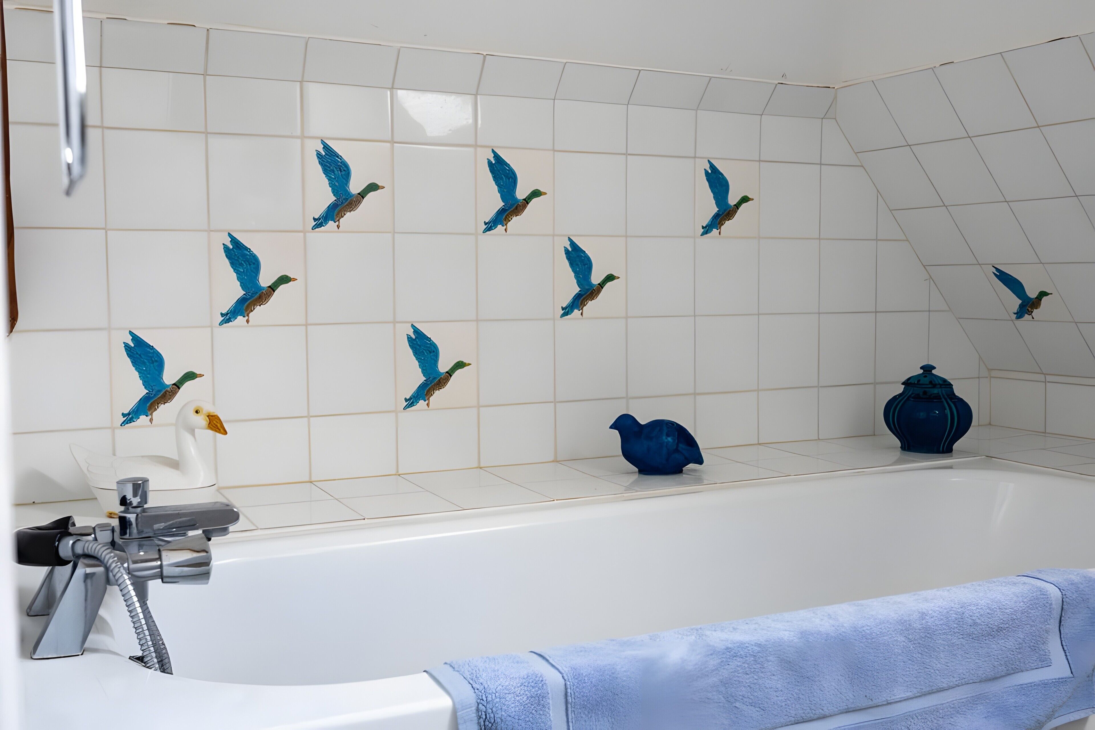 Un baño con bañera, ducha y una toalla azul.