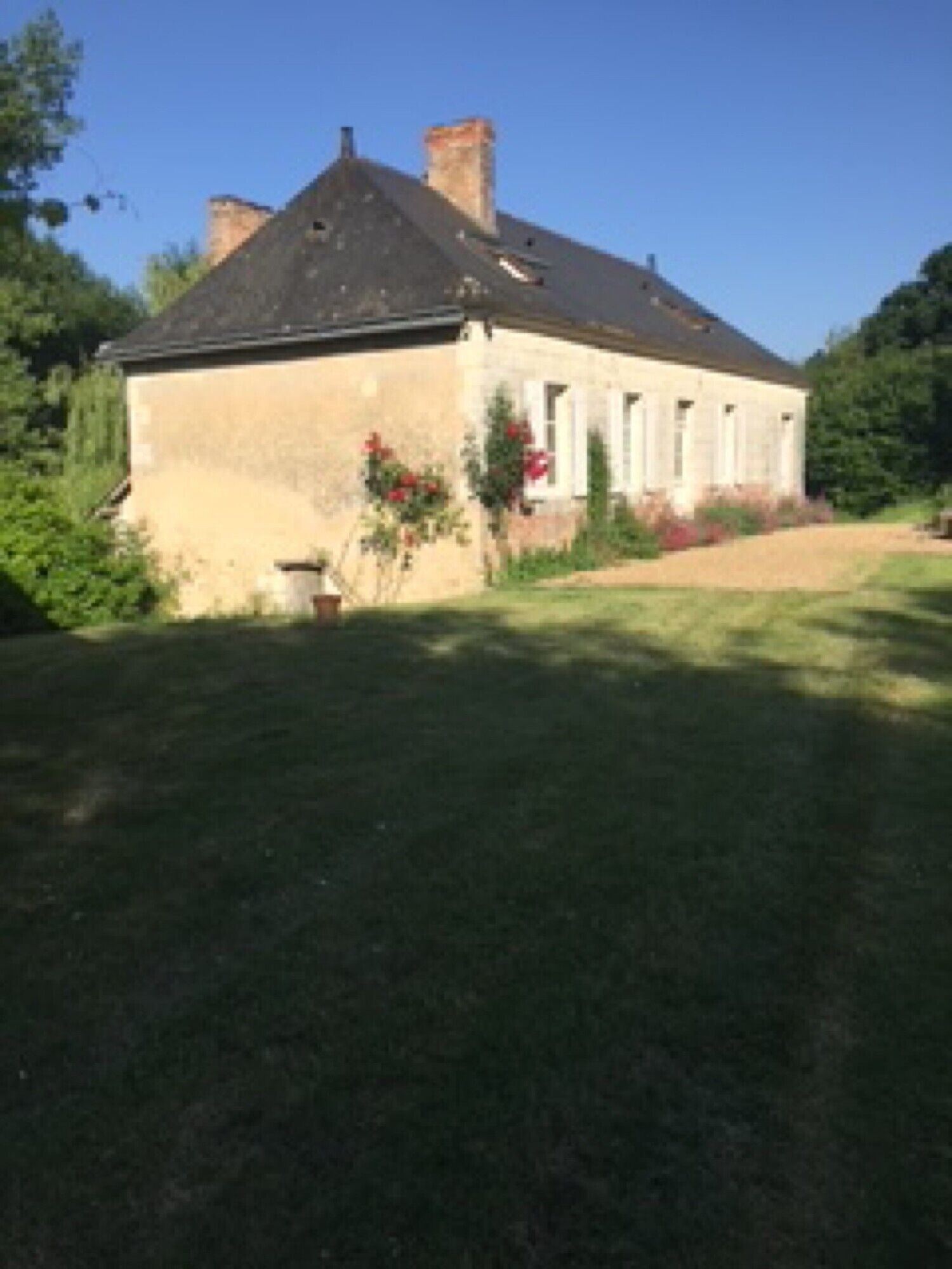 A two-story house with a sloped roof, a chimney, and a garden with a lawn and a flower bed.