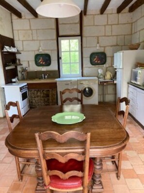Una cucina con un tavolo da pranzo, sedie, lavatrice, frigorifero e una finestra.