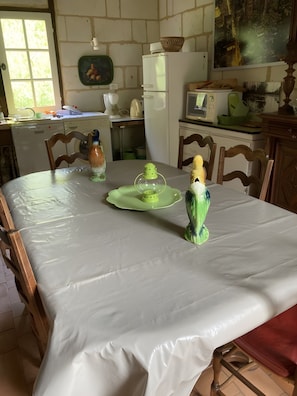 Ein Essbereich mit einem für zwei Personen gedecktem Tisch, Stühlen, einer grünen Tischläufer und einer dekorativen Vogelfigur.