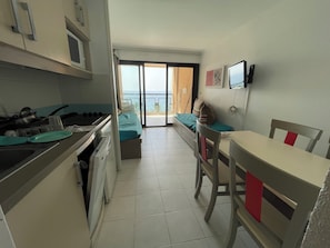 A compact kitchen with a dining area, a bed, and a view of the sea. - Studio facing the sea in Cannes la Bocca (Cannes)