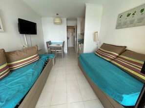 A room with two beds, a TV, a dining table, and a kitchen area. - Studio facing the sea in Cannes la Bocca (Cannes)