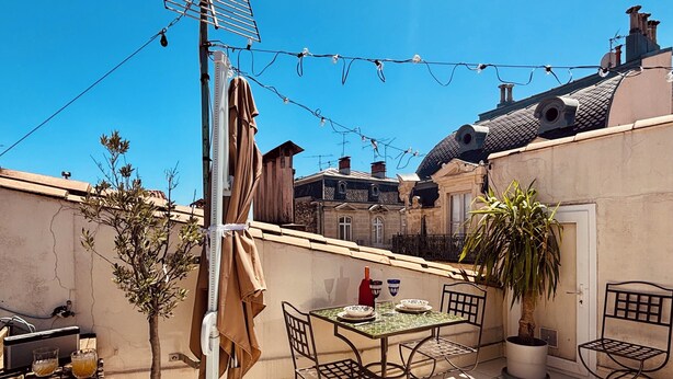 Eine Terrasse mit Tisch, Stühlen, einer Topfpflanze und einer Wäscheleine.