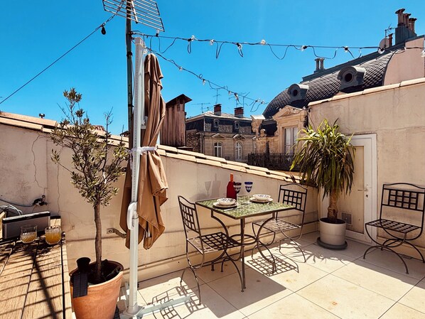Eine Terrasse mit Tisch, Stühlen, einer Topfpflanze und einer Wäscheleine.