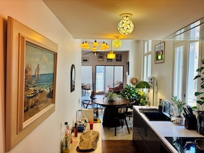 Eine moderne Küche mit Essbereich, einem großen Gemälde an der Wand und Blick durch die Glastür.
