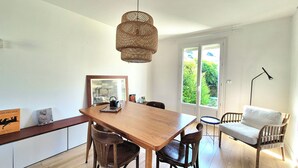 Ein Essbereich mit einem Holztisch, Stühlen, einer Pendelleuchte und Blick durch eine Glastür.