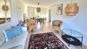 Ein modernes Wohnzimmer mit einer Couch, Sesseln, einem Esstisch und einem Glastisch.
