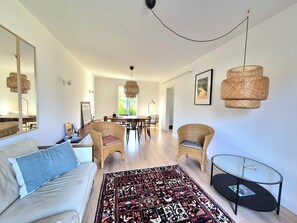 A modern living room with a sofa, chairs, a dining table, and a glass coffee table. - Bright Dinard home by the beach (Dinard)
