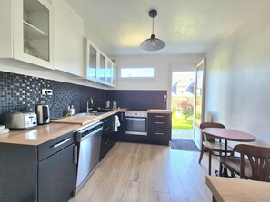 A modern kitchen with a wooden countertop, built-in appliances, and a view to the outside. - Bright Dinard home by the beach (Dinard)