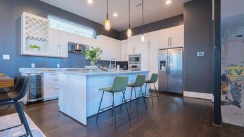 A modern kitchen with a central island, bar stools, and stainless steel appliances.