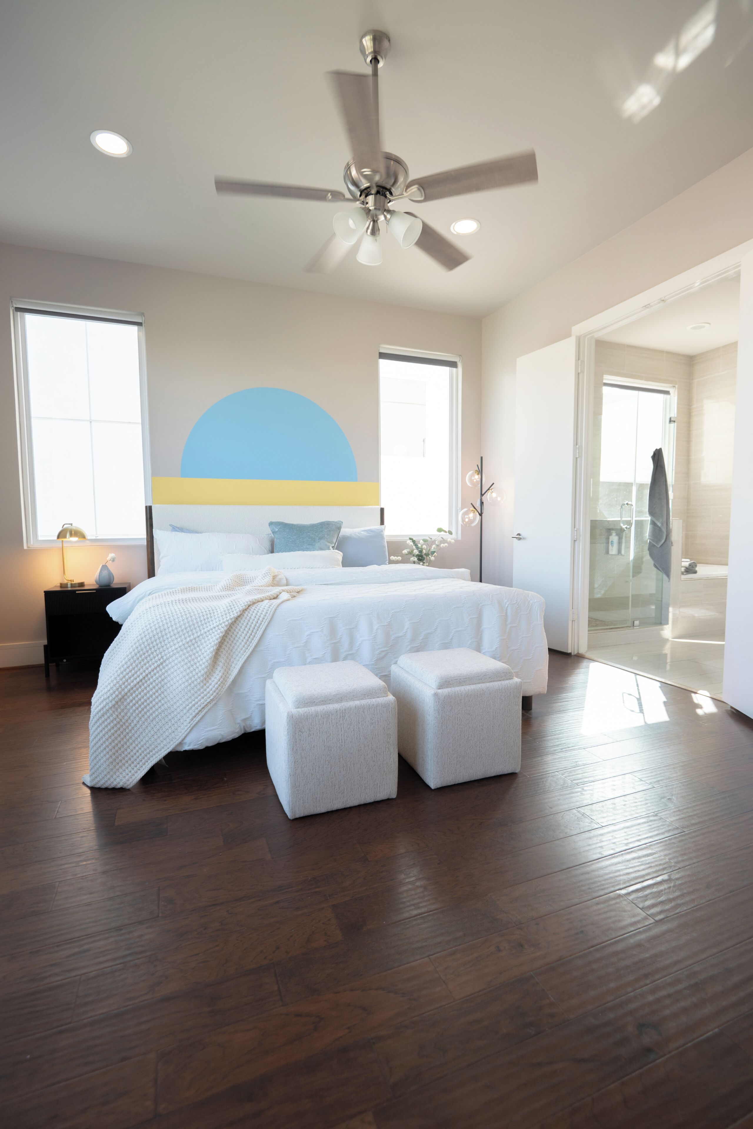 A bedroom with a bed, bedside tables, a ceiling fan, and a large window.