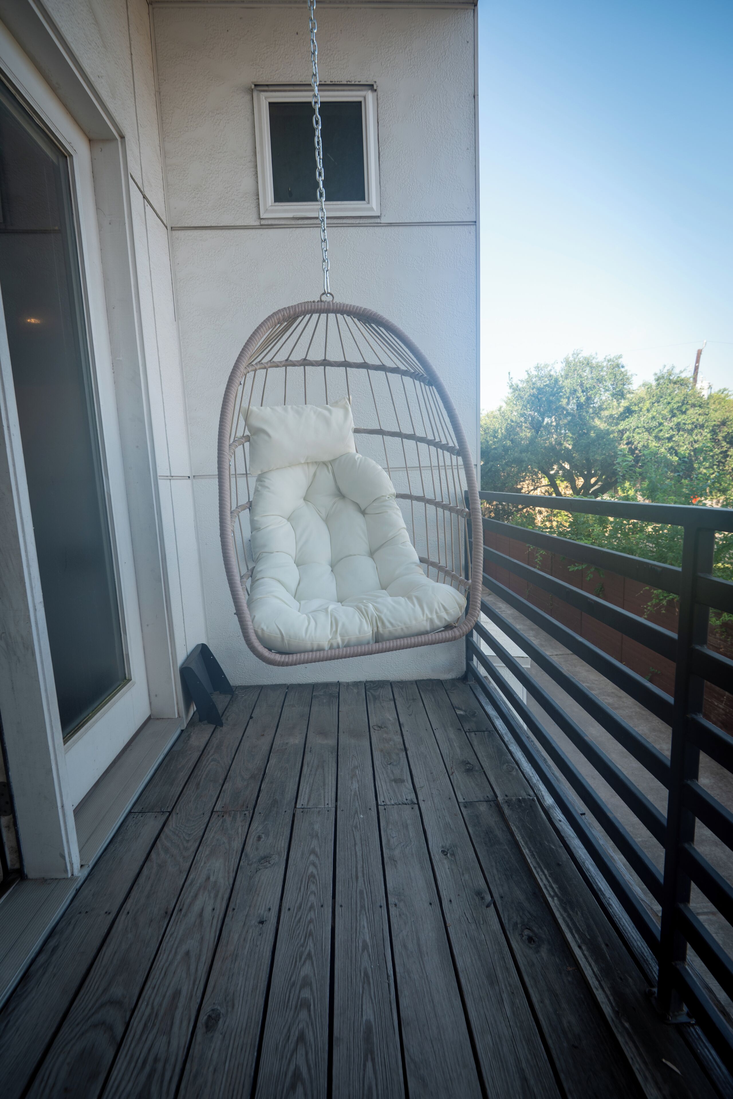 A wooden deck with a hanging chair and a small window.
