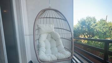 A wooden deck with a hanging chair and a small window.