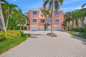 A multi-story building with a driveway, palm trees, and a well-maintained lawn.