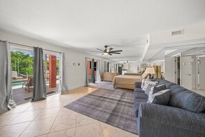 Ein geräumiges Zimmer mit einem großen Bett, einer Sitzecke und Blick auf einen Außenpool.