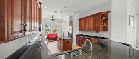 A modern kitchen with granite countertops, wooden cabinets, and a built-in dishwasher.