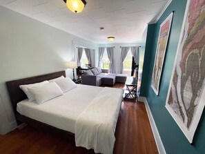 A hotel room with a large bed, a sofa, a desk, and a map on the wall. - Stylish Hotel Style Suite in Geneva`s Uptown Row (Geneva)