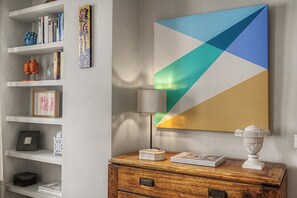 Ein Zimmer mit Bücherregal, Gemälde, Lampe und einem Holznachttisch.