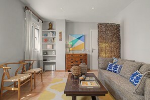 A living room with a sofa, a wooden coffee table, a bookshelf, and a decorative wall piece. - Mirador del Palmar Suite – Free Parking (Conil de la Frontera)