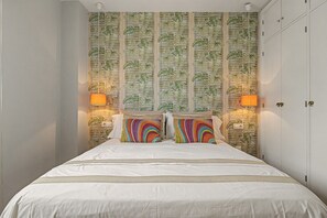 Ein Schlafzimmer mit einem Bett, Kissen und einer Wand mit einem Blattmuster.