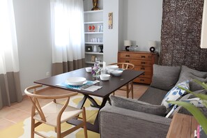 Ein Essbereich mit Tisch für zwei Personen, einer Couch, einem Holzschrank und einer Wanddekoration.