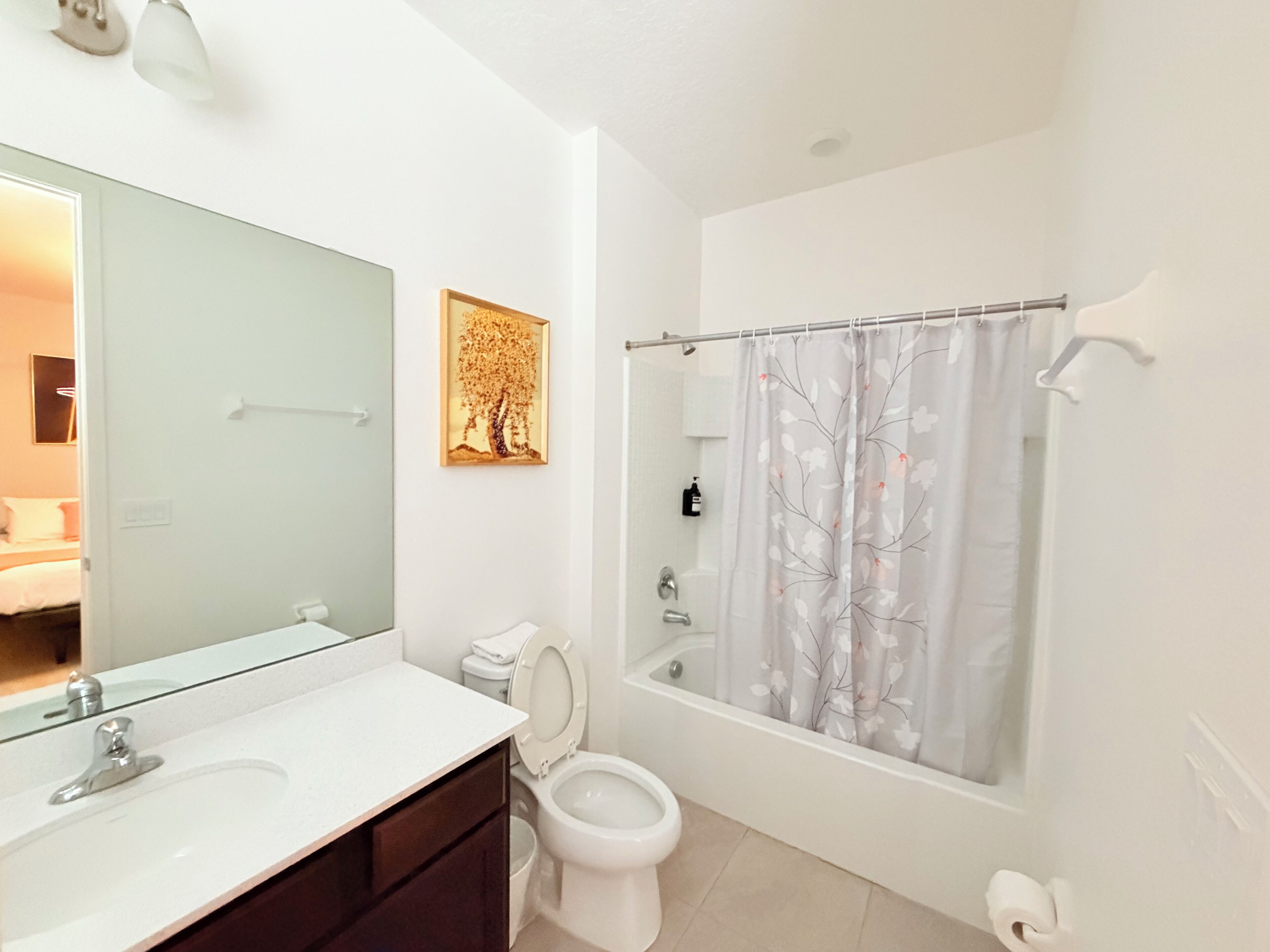 A modern bathroom with a large mirror, a toilet, a bathtub, and a shower curtain.
