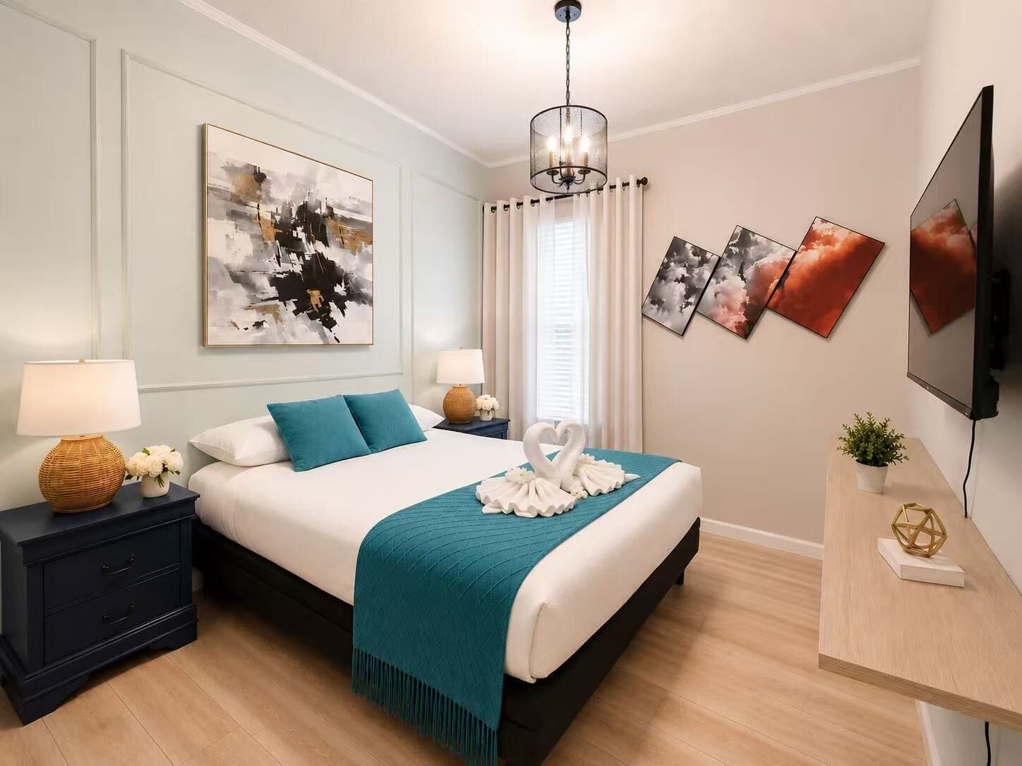 Une chambre d’hôtel moderne équipée d’un lit, de deux tables de chevet, d’un téléviseur, d’œuvres d’art et d’un lustre.