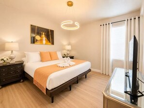 A hotel room with a bed, bedside tables, a TV, and a painting on the wall. - Grand Orion Twin Villas  24BR Resort Near Disney (Kissimmee)