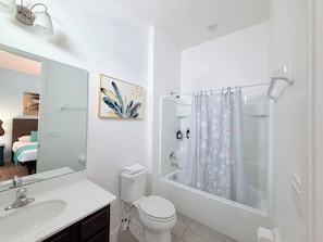 Un baño con bañera, inodoro, lavabo y un espejo grande.