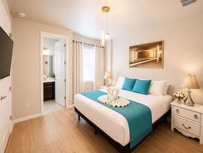 A hotel room with a bed, bedside tables, a mirror, a painting, and a TV. - Grand Orion Twin Villas  24BR Resort Near Disney (Kissimmee)