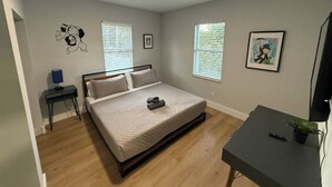Ein Schlafzimmer mit einem Bett, Nachttischen, einem Schreibtisch und einem Fernseher.