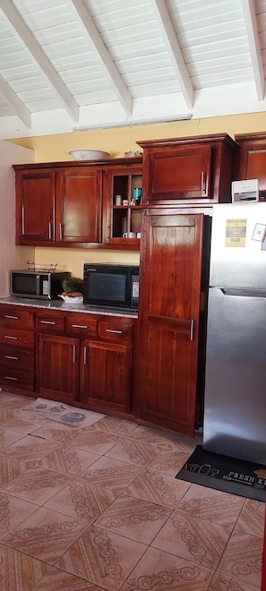 A kitchen with wooden cabinets, a microwave, a refrigerator, and a patterned floor.