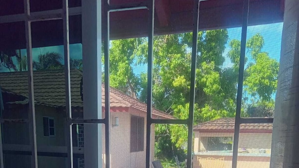 Näkymä ikkunasta, jossa näkyy uima-allas, tuoli ja taustalla oleva rakennus.