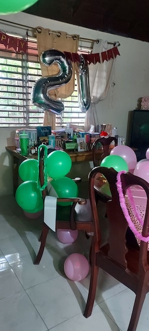 A room with a dining table, chairs, balloons, and a curtain with a '21' balloon.