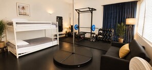 Ein kleines Zimmer mit Etagenbetten, einer Klimaanlage, einer Klimmzugstange und einem Squat-Gestell.