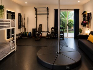 Ein Fitnessraum mit Klimmzugstange, Gewichtsheberbank und verschiedenen Trainingsgeräten.
